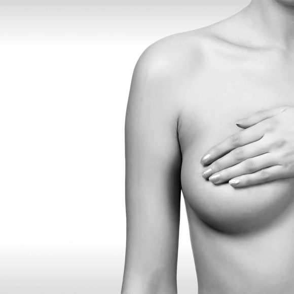 Woman controlling breast for cancer against a grey background with copyspace. Female healthcare concept
